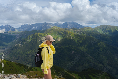 A young girl in a yellow hoodie and cap, a traveler in the Polish Tatras, the sky in the clouds.