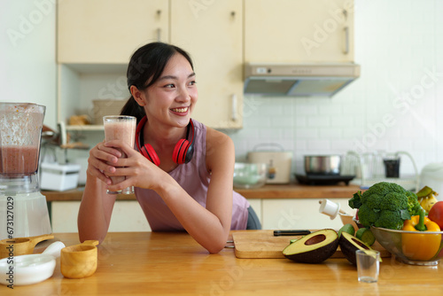 Young woman in Asian exercise clothes making a fruit and vegetable smoothie after a healthy workout at home. Concept of diet and healthy food  lifestyle