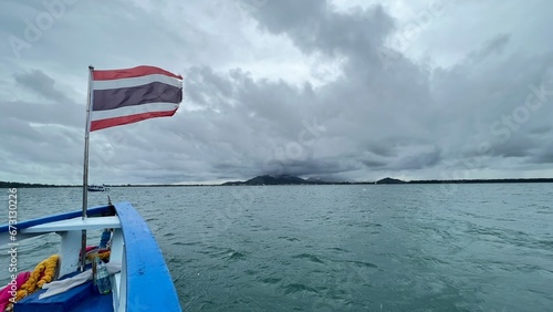 Thai Flag blowing in the wind in front of boat with storm cloud background.
