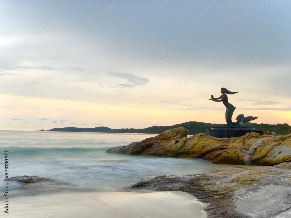 Silhouette of Mermaid statue at sunset on Sai Kaew beach in Samet island. ( Long exposure sea)