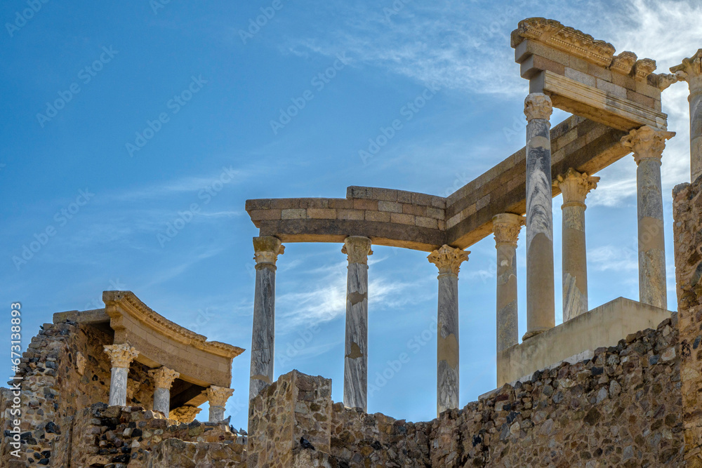 Back of the capitals, columns and cornices of the stage of the Roman theater in Mérida, with the midday sun illuminating the columns and ruins of the archaeological site.