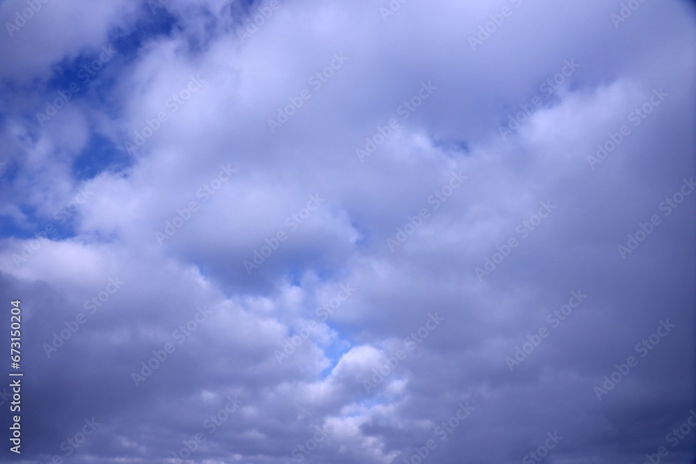 Beautiful cloud formations in the sky with sunlight behind. White clouds on dramatic blue sky at evening