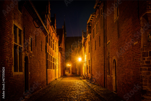 residential student houses in the Groot Begijnhof historic district of Leuven at night with streetlamp light. Atmospheric street photography showing old stone roads with pretty red brick buildings
