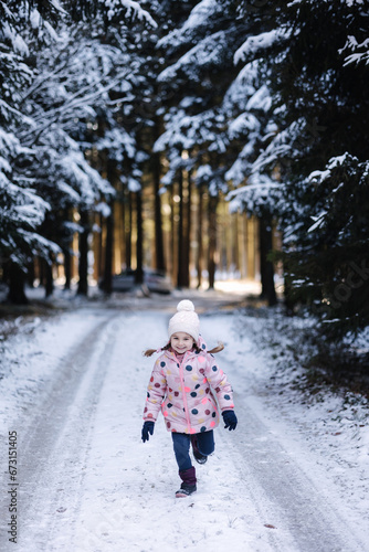 Fototapeta Naklejka Na Ścianę i Meble -  Adorable little girl run in snowy forest. Holiday mood