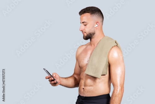 Calm confident handsome strong millennial european man with beard, naked torso, towel, wireless headphones