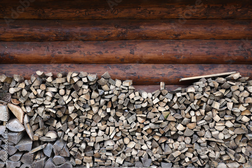 Firewood stacked near the wooden wall of old hut. Many chopped logs of firewood close up