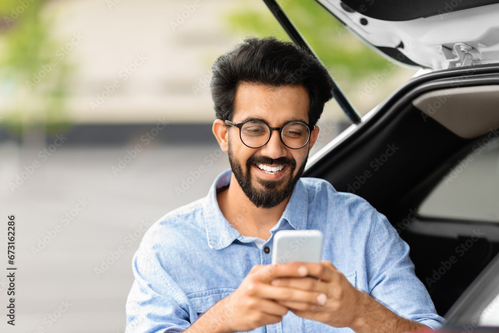 Closeup indian guy using smartphone, standing by car Closeup indian guy using smartphone, standing by car