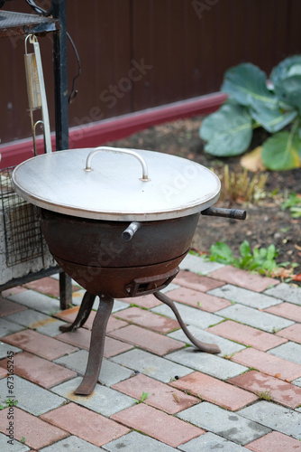 cauldron with a lid in the courtyard of a country house	 photo