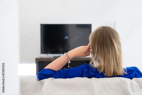 Fotografie Woman is waiting for a movie to load on the TV