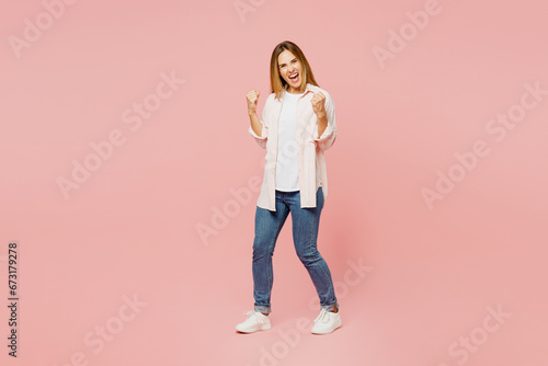 Full body side view young happy fun woman she wear shirt white t-shirt casual clothes do winner gesture clench fist isolated on plain pastel light pink background studio portrait. Lifestyle concept.