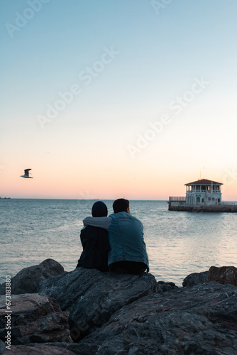 Photography Couple sitting on the beach and looking on the sunset