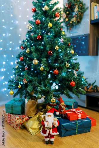 Santa and elves figurines near colorful gifts lying on the floor under the Christmas tree