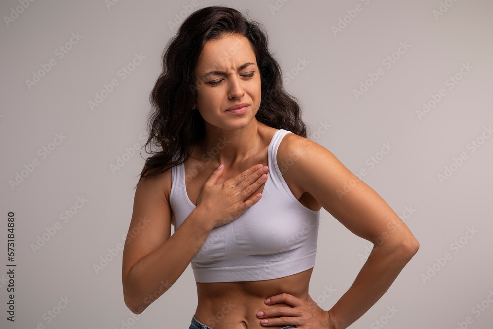 Sick millennial woman in white top suffering from heartburn Sick millennial woman in white top suffering from heartburn