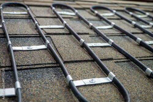 Electric roof heating system. Wire is fixed to tile. Cable for heating roof in winter. Equipment for cleaning roof from snow. Electric heating wire with metal fastening. Roofing, housetop