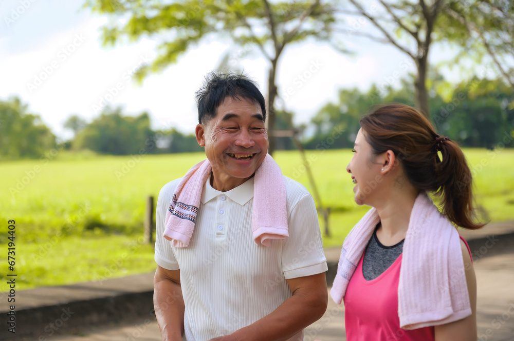 Asian Elderly Father and Daughter are walking relaxing in a green park, Breathing in the fresh air and enjoying the beautiful scenery. Healthcare and family bonding. Asian Elderly Father and Daughter are walking relaxing in a green park, Breathing in the fresh air and enjoying the beautiful scenery. Healthcare and family bonding.