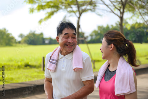Asian Elderly Father and Daughter are walking relaxing in a green park, Breathing in the fresh air and enjoying the beautiful scenery. Healthcare and family bonding.
