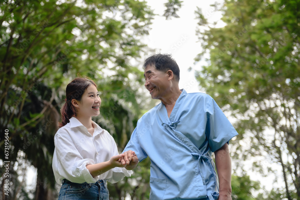 Daughter takes care of father and helps Support, Encourage him during his illness at hospital garden. The happiness of old adult patients while rehabilitation or physical therapy of retired patients. Daughter takes care of father and helps Support, Encourage him during his illness at hospital garden. The happiness of old adult patients while rehabilitation or physical therapy of retired patients.