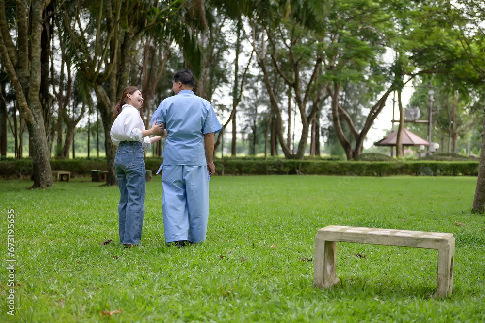 Daughter takes care of father and helps Support, Encourage him during his illness at hospital garden. The happiness of old adult patients while rehabilitation or physical therapy of retired patients. Daughter takes care of father and helps Support, Encourage him during his illness at hospital garden. The happiness of old adult patients while rehabilitation or physical therapy of retired patients.