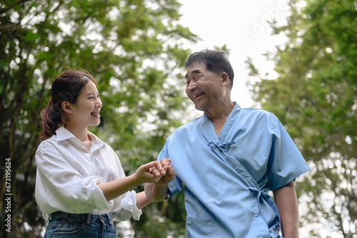 Daughter takes care of father and helps Support, Encourage him during his illness at hospital garden. The happiness of old adult patients while rehabilitation or physical therapy of retired patients.