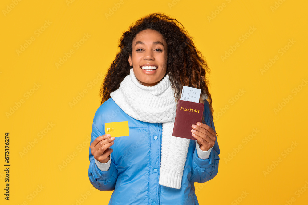 happy young black lady with travel documents and credit card on yellow background happy young black lady with travel documents and credit card on yellow background