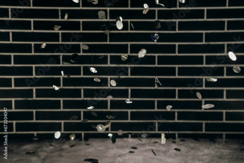 Pile of coins falling onto the floor, with a brick wall as the backdrop. photo