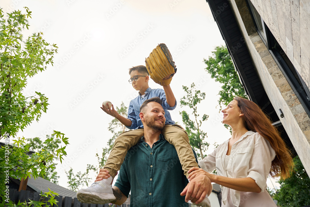 Man carries his son with baseball gadgets on his shoulders