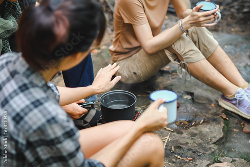 People Trekking Group Boil Water and Check Water Temperature by Hand while Holding the Cup. Boil Water for Clean and Hygiene in the Forest. Campsite Drinking Coffee and Clean Water on Trekking Trips.