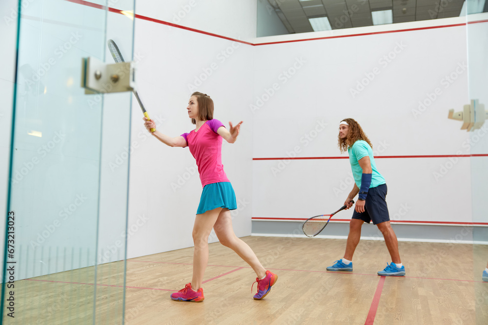 People playing squash enjoying recreational pursuit at indoor training club People playing squash enjoying recreational pursuit at indoor training club