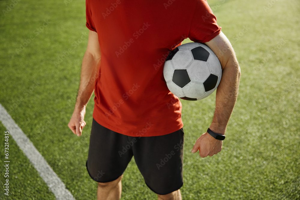 Crop view of football trainer or soccer player holding ball