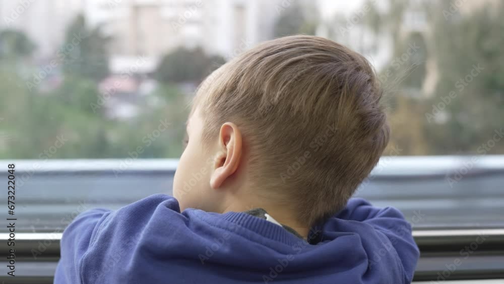 A five-year-old boy rides and looks out the window A five-year-old boy rides and looks out the window