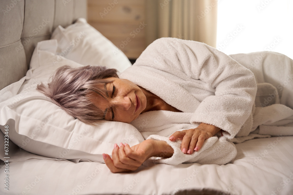 Elderly woman sleeps sweetly in bright bedroom on soft pillows Elderly woman sleeps sweetly in bright bedroom on soft pillows
