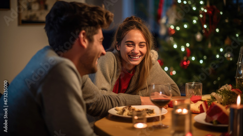 Smiling couple close together at a festive Christmas dinner setting, with lit candles and a decorated tree in the background, creating a warm and intimate atmosphere.