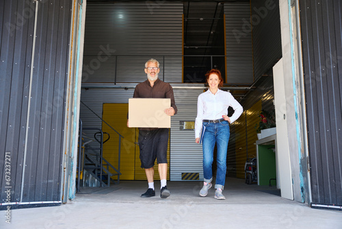 Woman with a blue folder and man walk through warehouse