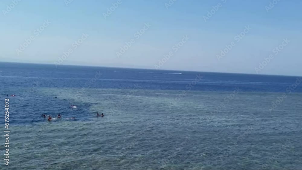 Some people are snorkelling in the Blue Hole, Dahab, South Sinai, Egypt. There is a launch moving near them. The Blue Hole is famous for snorkelling and diving. It's called Diver's Cemetery. Some people are snorkelling in the Blue Hole, Dahab, South Sinai, Egypt. There is a launch moving near them. The Blue Hole is famous for snorkelling and diving. It's called Diver's Cemetery.