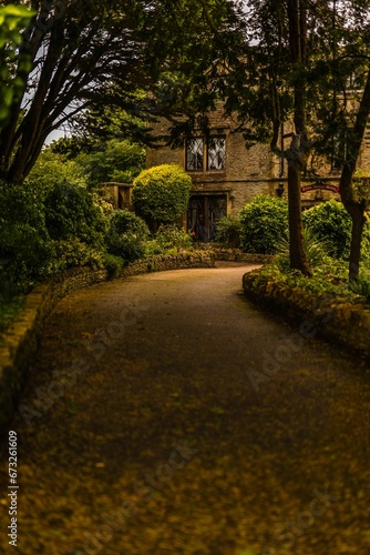 Path in the yard of a picturesque stone house nestled among lush greenery.