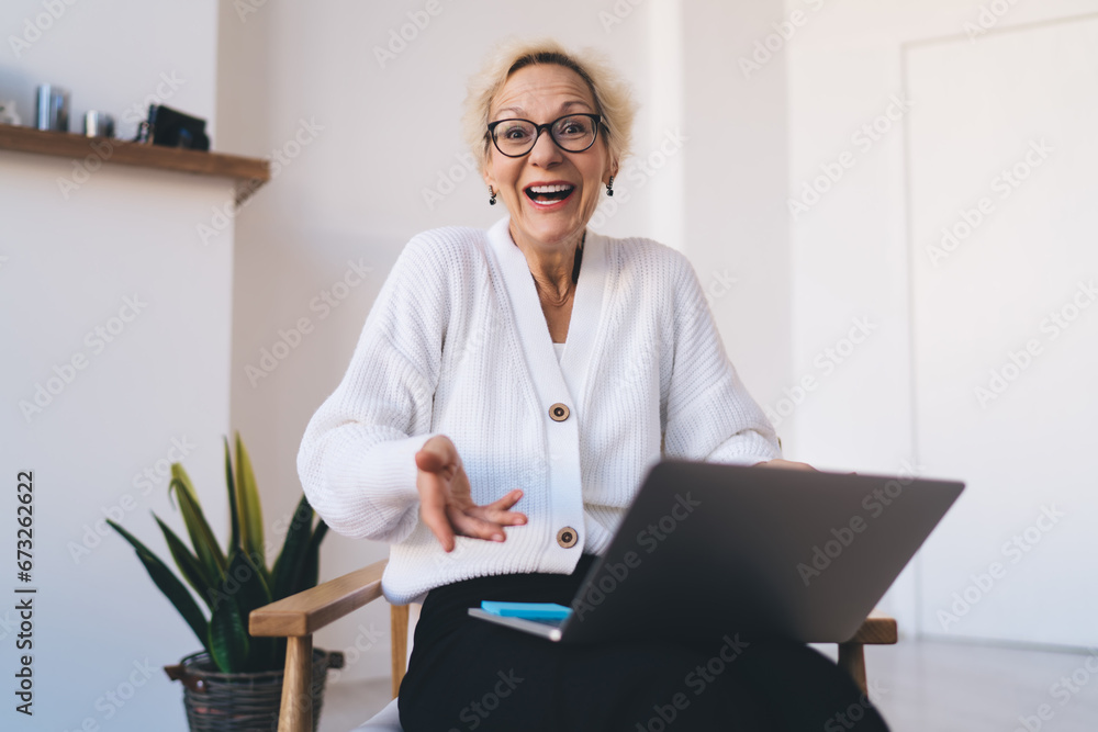CConfised mature woman sitting in armchair with laptop at home CConfised mature woman sitting in armchair with laptop at home