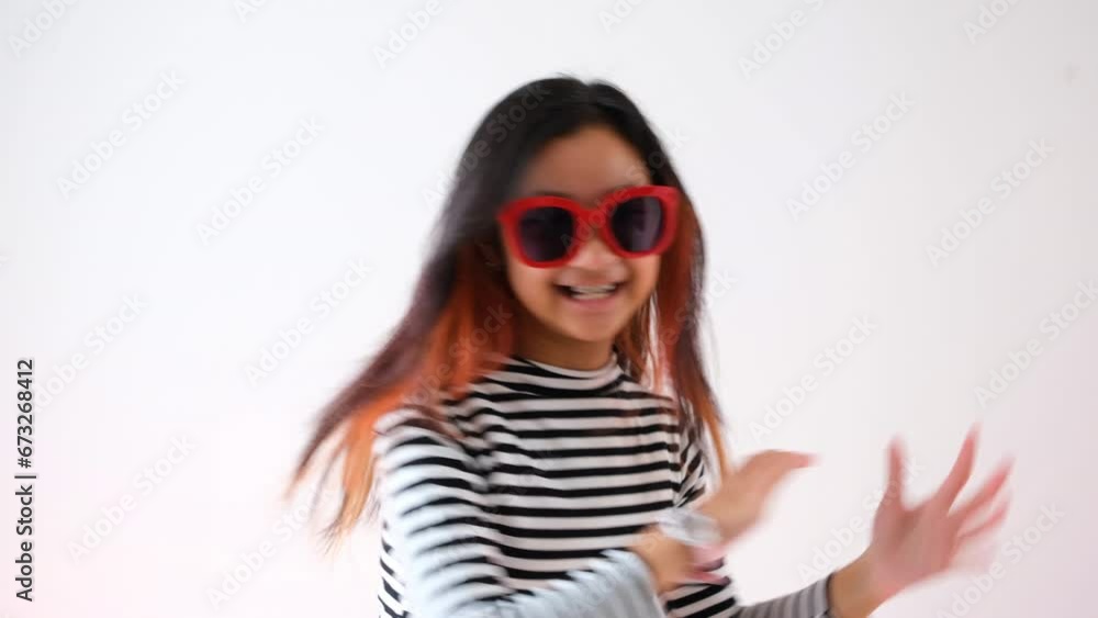 Asian teenage girl with fashionable hair dye, wearing a black and white striped long-sleeved t-shirt and red sunglasses, is dancing with a smiling face.