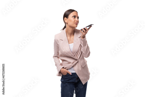 young joyful business woman leader with a ponytail hairstyle dressed in a beige jacket speaks on the phone