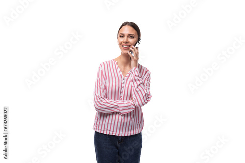 a young smart European woman with black hair gathered in a ponytail is dressed in a red and white striped blouse speaks on the phone photo