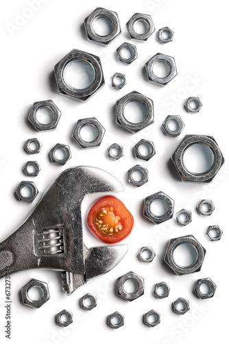 Conceptual image of a wrench, nuts and a cherry tomato slice on white background. photo