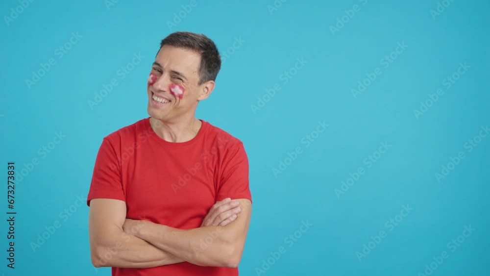 Man standing with swiss flag painted on face smiling Man standing with swiss flag painted on face smiling