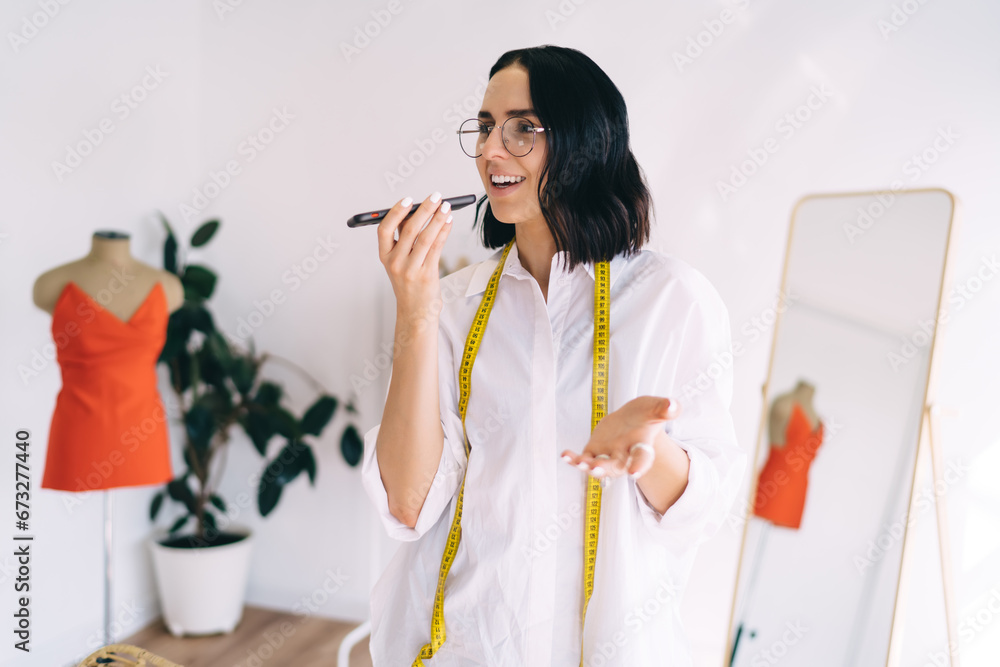Smiling craftswoman talking on loudspeaker on smartphone Smiling craftswoman talking on loudspeaker on smartphone