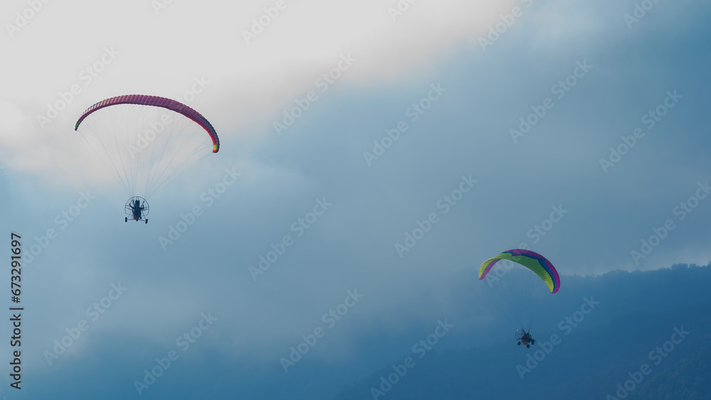 Flying with paramotor in the blue sky - Man riding paramotor in the blue sky background Flying with paramotor in the blue sky - Man riding paramotor in the blue sky background