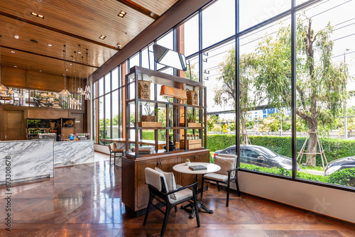 Modern cafe interior with large windows  wooden furniture  marble countertop  hanging bulbs  and indoor greenery.