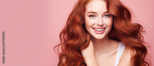 Beautiful elegant european red-haired smiling young woman with perfect skin and long red hair, on a pink background, close-up