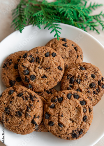 Chocolate cookies on a plate with spruce branches on the table. Dark chocolate cookies on a plate, Christmas cookies chocolate cinnamon sweet dessert holiday treat new year and christmas food