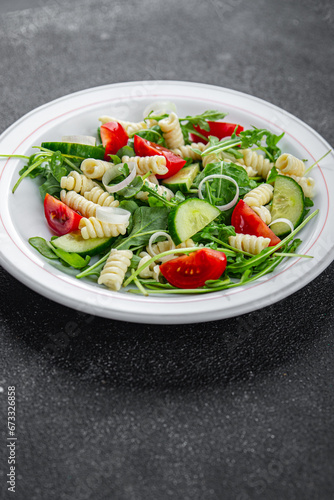 pasta salad fusilli pasta, cucumber, tomato, green lettuce cooking eating appetizer meal food snack on the table copy space food background rustic top view keto or paleo diet vegetarian