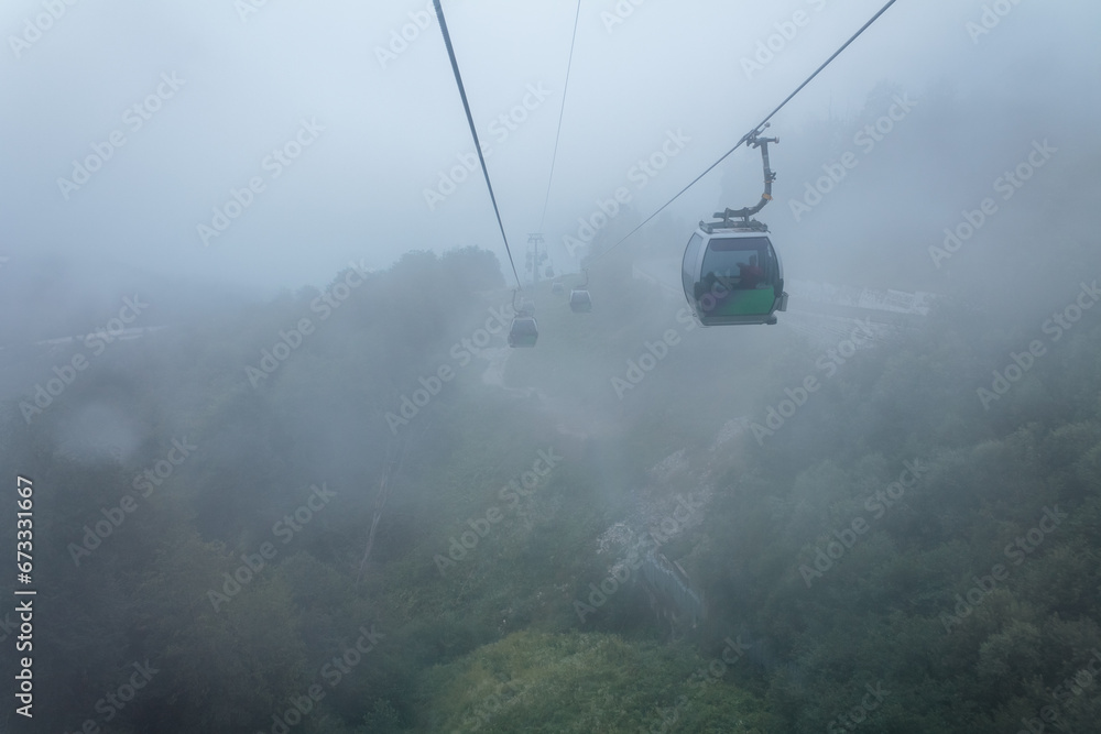 Cable car cabin in the mountains, during fog and clouds, rising up the slope