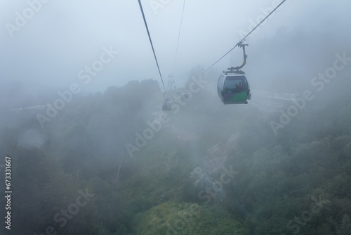 Cable car cabin in the mountains, during fog and clouds, rising up the slope