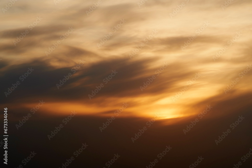 Sunset sky with red light of the setting sun. Evening clouds in the orange light of sunset rays
